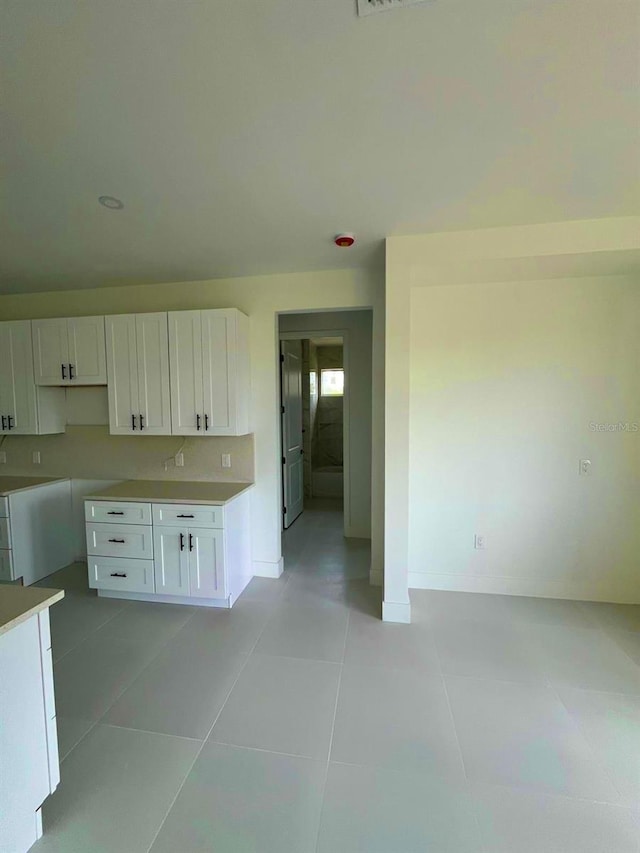 1043 Brenton Ave, Lehigh Acres, FL 33974 - kitchen featuring white cabinetry, light tile patterned flooring, baseboards, and light countertops