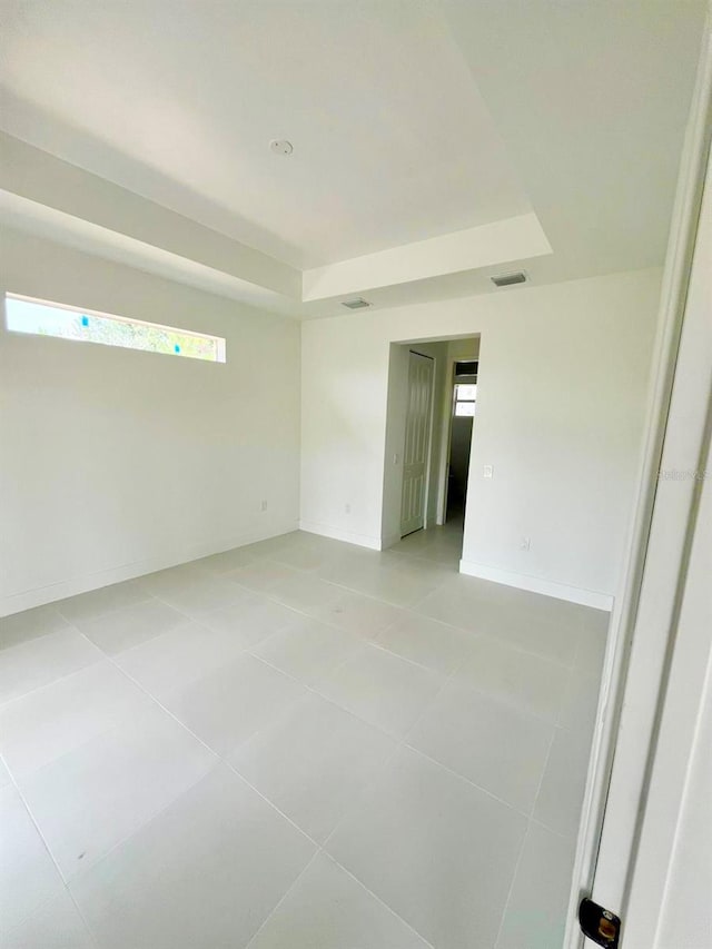 1043 Brenton Ave, Lehigh Acres, FL 33974 - empty room with light tile patterned flooring, a tray ceiling, and baseboards