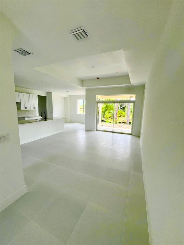 1043 Brenton Ave, Lehigh Acres, FL 33974 - unfurnished living room with a tray ceiling, baseboards, and a sink