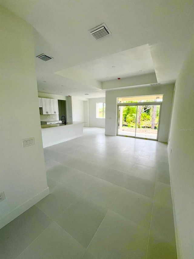 1043 Brenton Ave, Lehigh Acres, FL 33974 - empty room with a tray ceiling, baseboards, and a sink