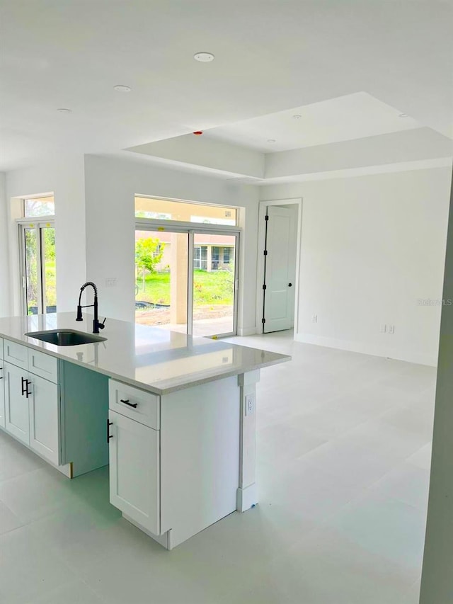 1043 Brenton Ave, Lehigh Acres, FL 33974 - kitchen featuring a sink, open floor plan, an island with sink, white cabinets, and a raised ceiling