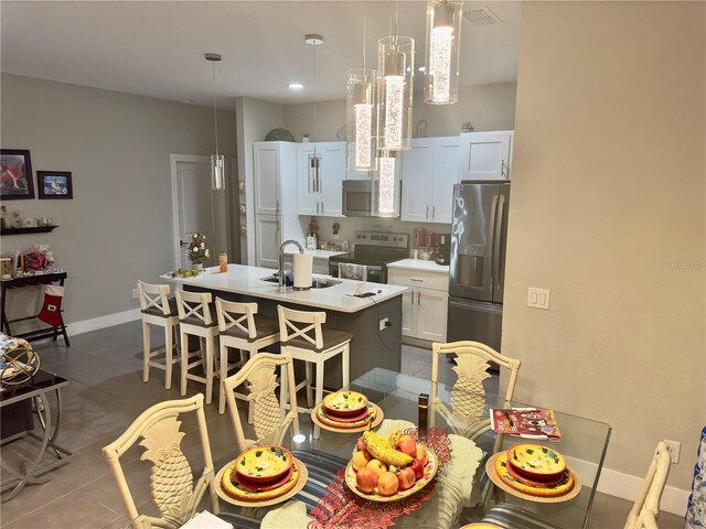 1804 Hudson Ct, Poinciana, FL 34759 - kitchen featuring a breakfast bar, light countertops, a center island with sink, stainless steel appliances, and a sink
