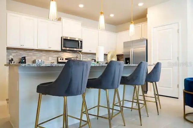 3834 Lana Ave, Davenport, FL 33897 - kitchen featuring tasteful backsplash, a breakfast bar, white cabinets, stainless steel appliances, and hanging light fixtures