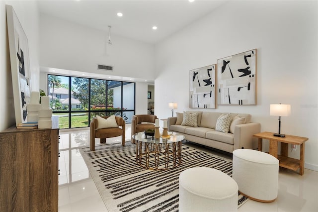 tiled living area featuring a high ceiling, baseboards, visible vents, and recessed lighting