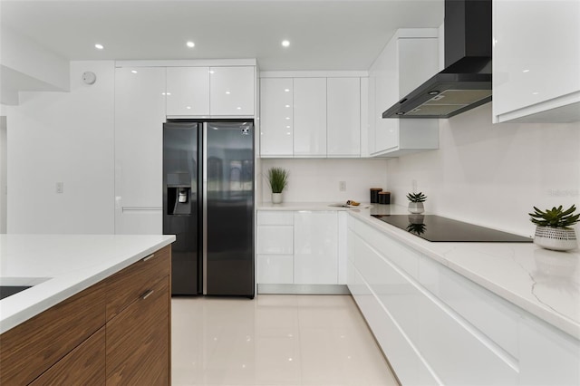 kitchen featuring fridge with ice dispenser, black electric stovetop, wall chimney range hood, white cabinets, and modern cabinets