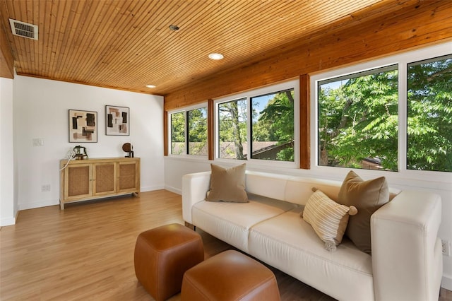 living room featuring light wood finished floors, visible vents, baseboards, and wood ceiling