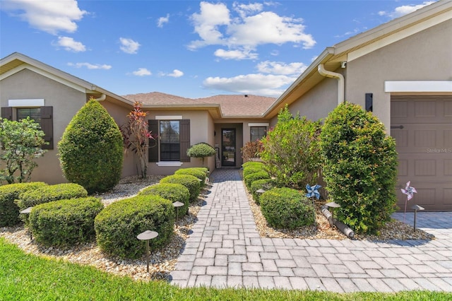 entrance to property with stucco siding and a garage