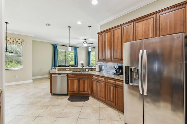 kitchen featuring brown cabinets, stainless steel appliances, a peninsula, and a sink