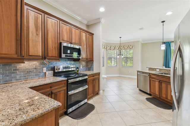 kitchen with backsplash, appliances with stainless steel finishes, light tile patterned flooring, brown cabinetry, and hanging light fixtures