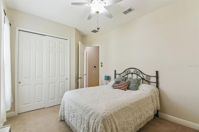 bedroom with a closet, visible vents, light colored carpet, and baseboards