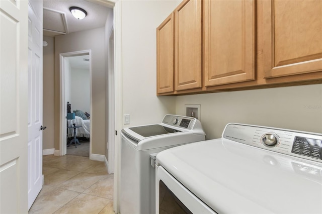 laundry area featuring baseboards, light tile patterned floors, cabinet space, and washer and clothes dryer