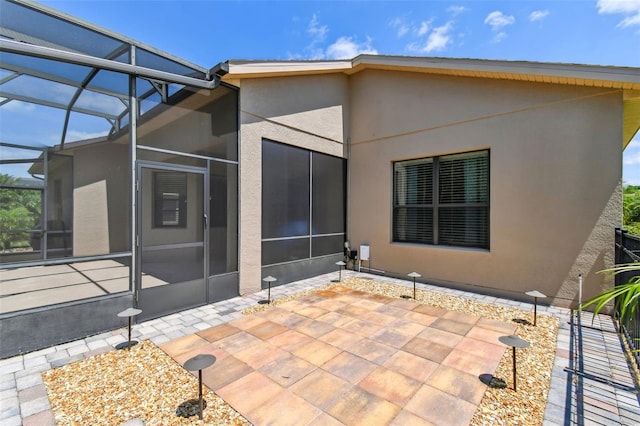 back of property featuring a patio, glass enclosure, and stucco siding