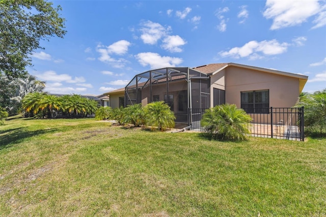back of property with glass enclosure, stucco siding, and a yard