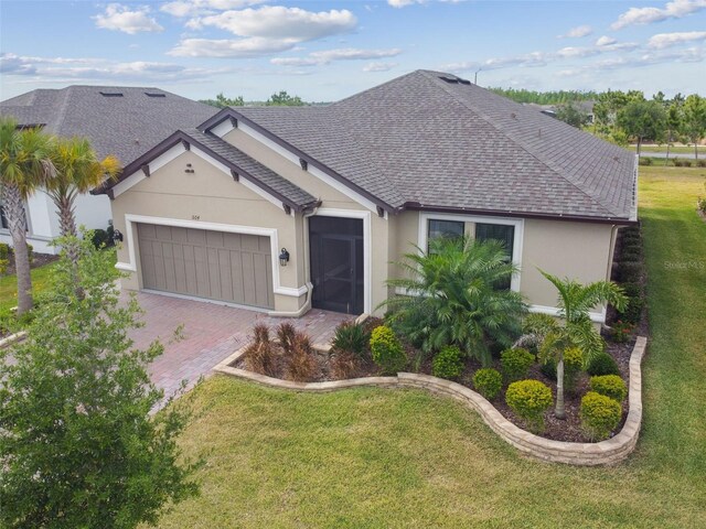 204 Bella Cortina Dr, Kissimmee, FL 34759 - ranch-style house featuring stucco siding, roof with shingles, a front yard, an attached garage, and decorative driveway