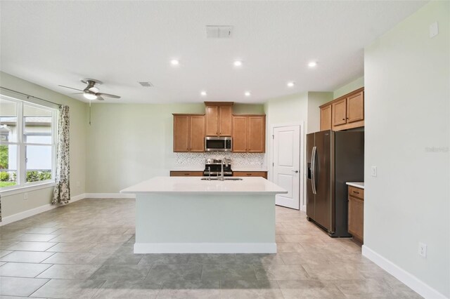 204 Bella Cortina Dr, Kissimmee, FL 34759 - kitchen featuring appliances with stainless steel finishes, a sink, backsplash, brown cabinetry, and recessed lighting
