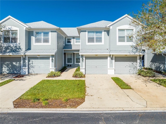 view of property with an attached garage, driveway, and stucco siding