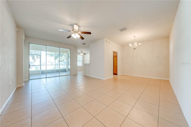 empty room with baseboards, light tile patterned floors, a textured ceiling, visible vents, and ceiling fan with notable chandelier