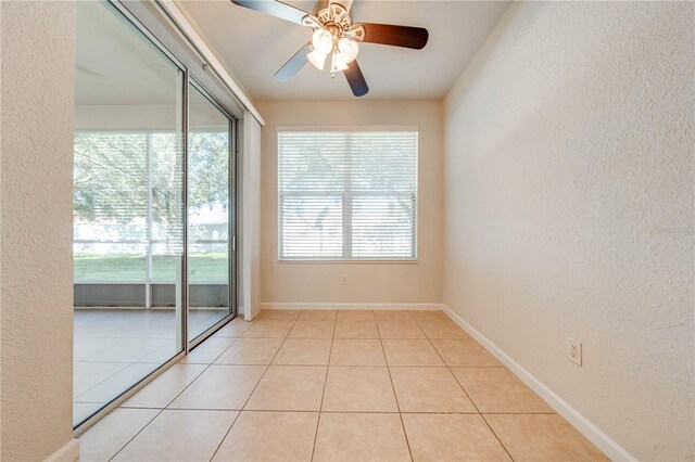 spare room with tile patterned floors, ceiling fan, a textured wall, and baseboards
