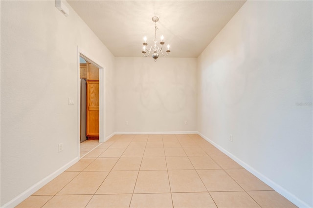 spare room featuring light tile patterned flooring, a notable chandelier, and baseboards