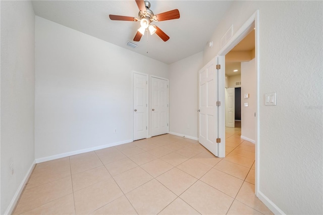 unfurnished bedroom with light tile patterned floors, visible vents, baseboards, and a ceiling fan