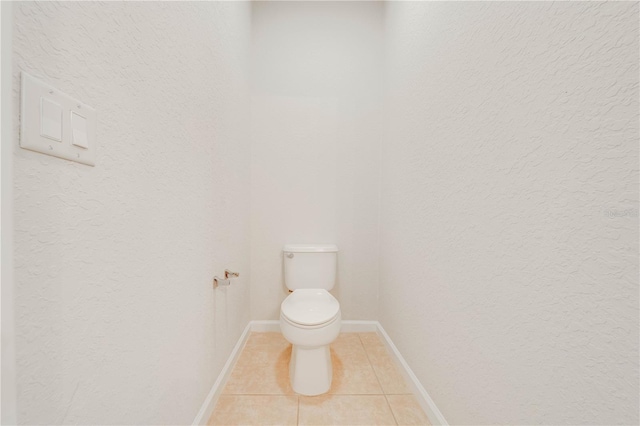 bathroom with tile patterned floors, baseboards, and toilet