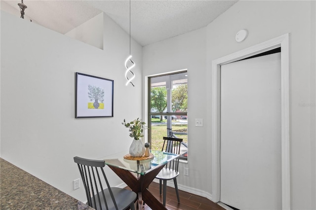 dining room featuring a textured ceiling, dark wood-style flooring, and baseboards