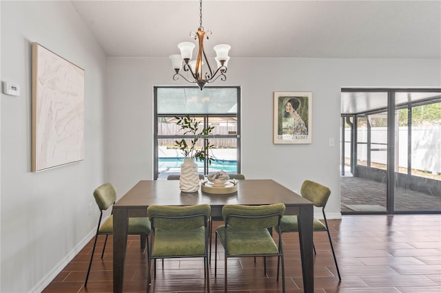 dining space featuring baseboards, an inviting chandelier, and wood finished floors