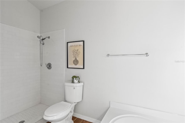 bathroom featuring a tile shower and toilet