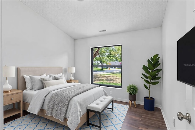 bedroom featuring a textured ceiling, baseboards, and wood finished floors