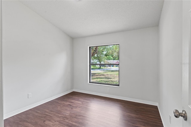 spare room with a textured ceiling, baseboards, and dark wood finished floors