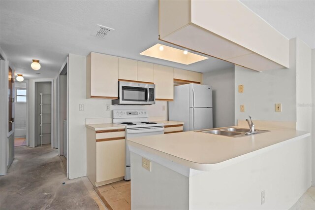 2745 N Poinciana Blvd Unit 65, Kissimmee, FL 34746 - kitchen with visible vents, a sink, white appliances, a peninsula, and cream cabinetry