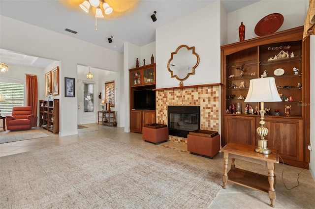 469 Sorrento Rd, Kissimmee, FL 34759 - living area with visible vents, light tile patterned floors, built in shelves, a brick fireplace, and a ceiling fan