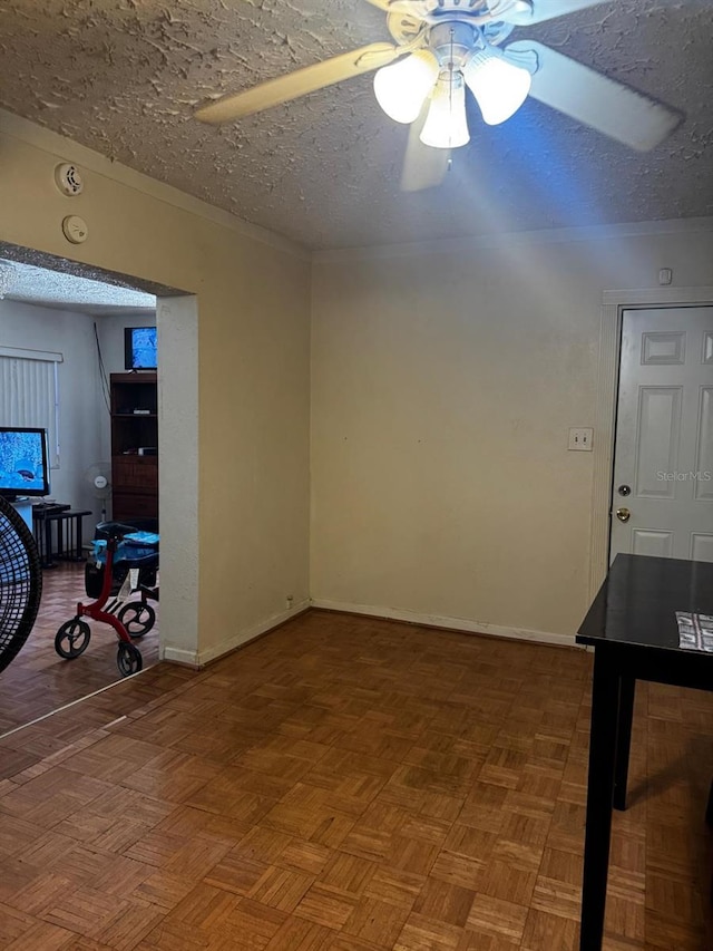 unfurnished room featuring baseboards, a textured ceiling, and ceiling fan