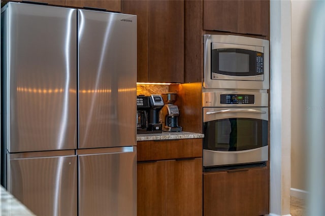 9509 Baycliff Ct, Orlando, FL 32836 - kitchen with appliances with stainless steel finishes, light countertops, modern cabinets, tasteful backsplash, and brown cabinets