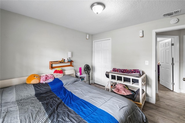 2804 Robinson Rd, Plant City, FL 33565 - bedroom featuring a textured ceiling, a closet, visible vents, wood finished floors, and baseboards