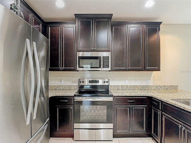 328 Vestrella Dr, Poinciana, FL 34759 - kitchen featuring stainless steel appliances, a textured ceiling, backsplash, and light stone counters