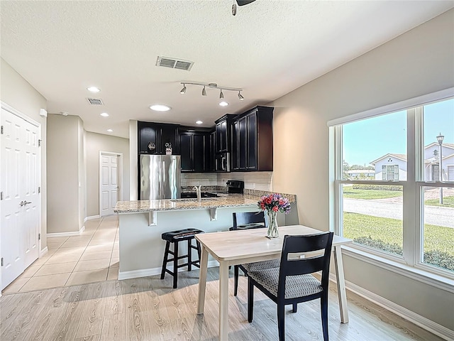 328 Vestrella Dr, Poinciana, FL 34759 - kitchen featuring dark cabinets, a peninsula, light stone counters, a sink, and stainless steel fridge
