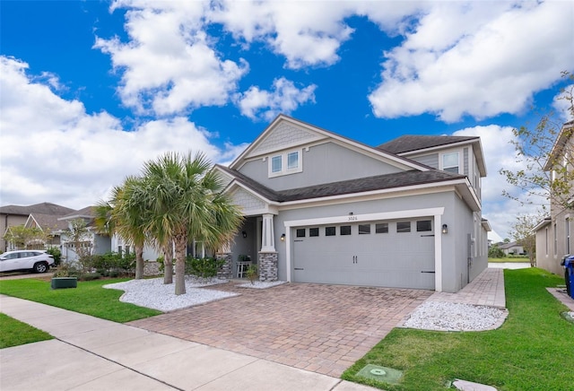 craftsman-style home featuring an attached garage, stone siding, decorative driveway, and a front lawn