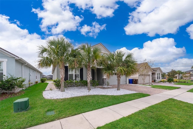 view of front facade with a garage, a front yard, stucco siding, and decorative driveway