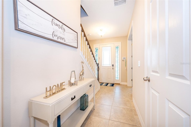 entryway featuring light tile patterned floors, baseboards, visible vents, and stairs