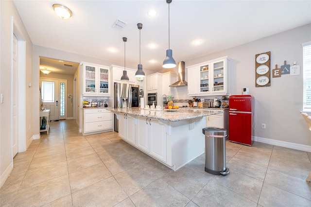 kitchen featuring visible vents, light tile patterned floors, wall chimney range hood, appliances with stainless steel finishes, and a kitchen breakfast bar