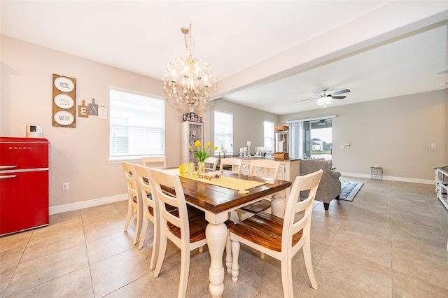 dining area with ceiling fan with notable chandelier, light tile patterned flooring, and baseboards