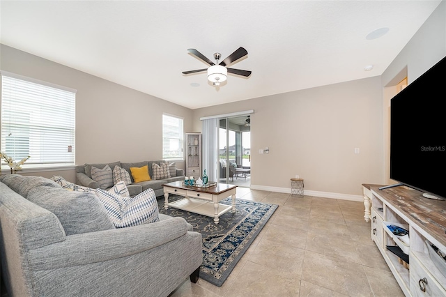 living area with light tile patterned floors, baseboards, and ceiling fan