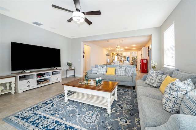 living room featuring visible vents, ceiling fan with notable chandelier, and baseboards