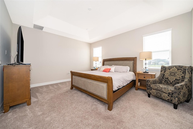 bedroom featuring visible vents, baseboards, a raised ceiling, and light colored carpet