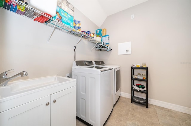 clothes washing area featuring baseboards, a sink, cabinet space, and washer and clothes dryer