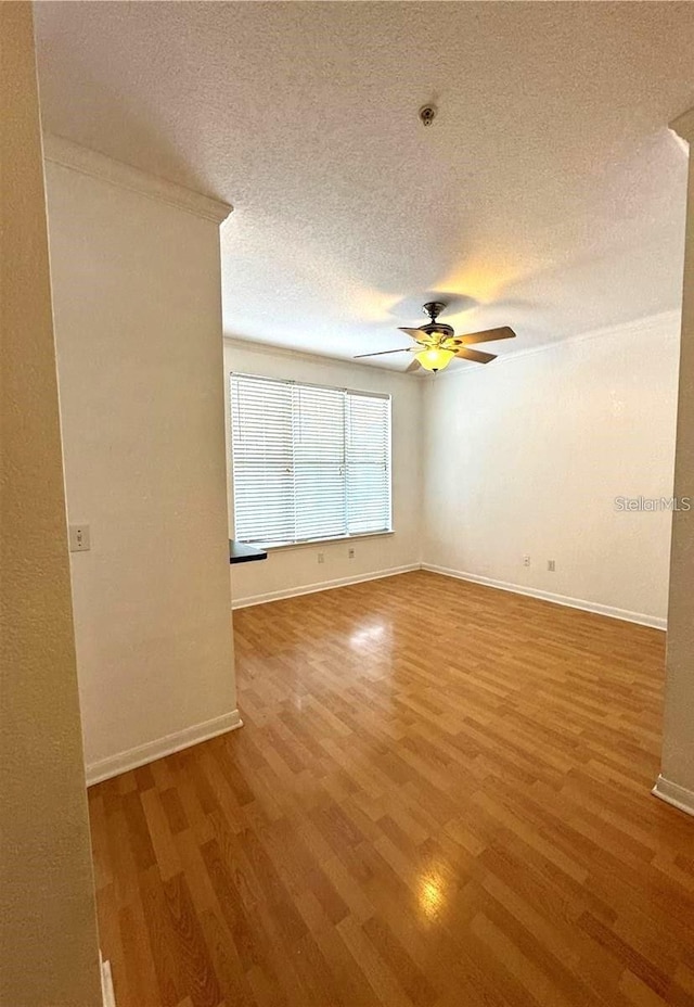 unfurnished room with a textured ceiling, wood finished floors, and a ceiling fan