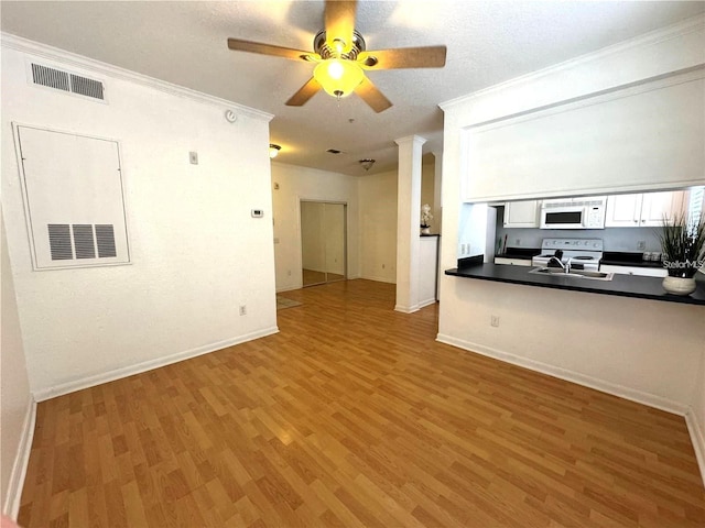 kitchen featuring white appliances, crown molding, dark countertops, visible vents, and light wood finished floors