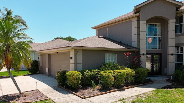 view of home's exterior with french doors, a garage, stucco siding, and driveway
