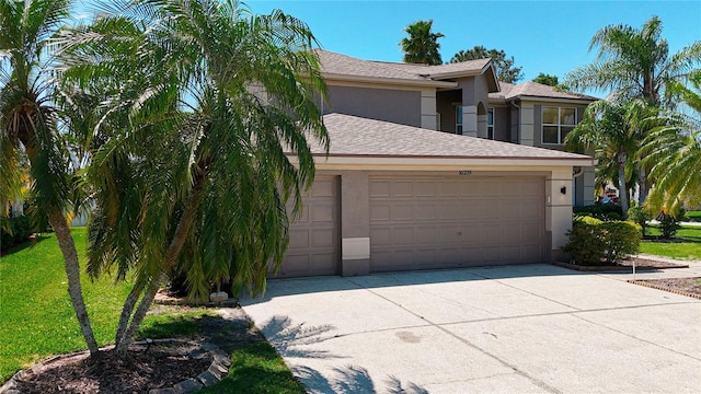 view of front of house with concrete driveway, a front yard, an attached garage, and stucco siding